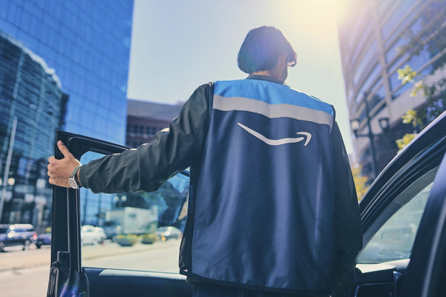 Amazon delivery driver opening car door on urban street with modern buildings in background